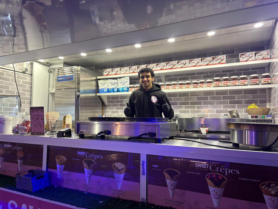 Ahmed Mikail (19) st&aring;r i foodtrucken han jobber i p&aring; julemarkedet. 
