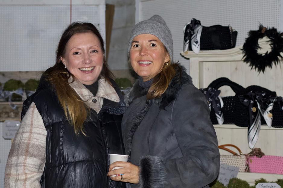 Therese Lunde og Irene Borge-Hansen st&aring;r foran julemarkedet.