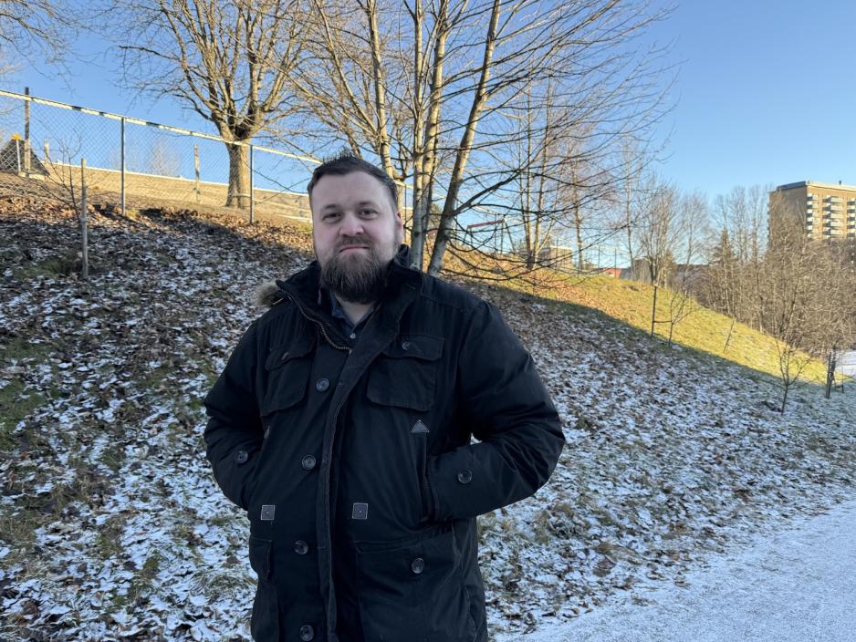 Mann i svart k&aring;pe i en park