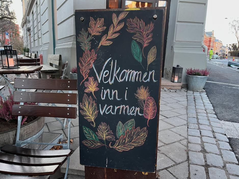 Skilt hvit det st&aring;r "Velkommen inn", utenfor &Aring;pent Bakeri p&aring; Frogner