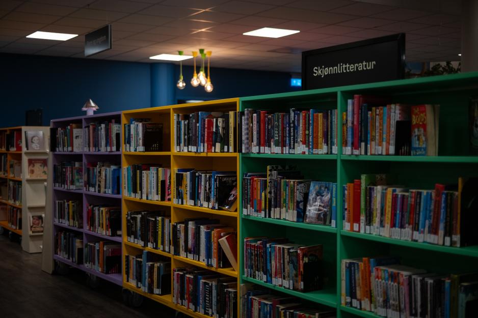 Biblioteks hyller fylt med b&oslash;ker med et skilt som sier "Skj&oslash;nnlitteratur"