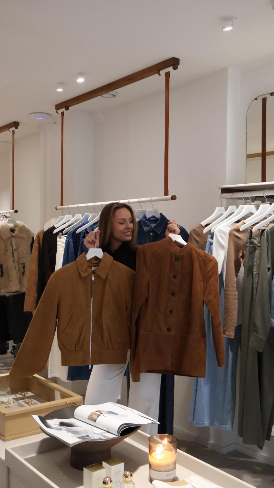 Butikkansatt holder opp to semsket skinn ajkker som hun mener blir v&aring;rens st&oslash;rste trend