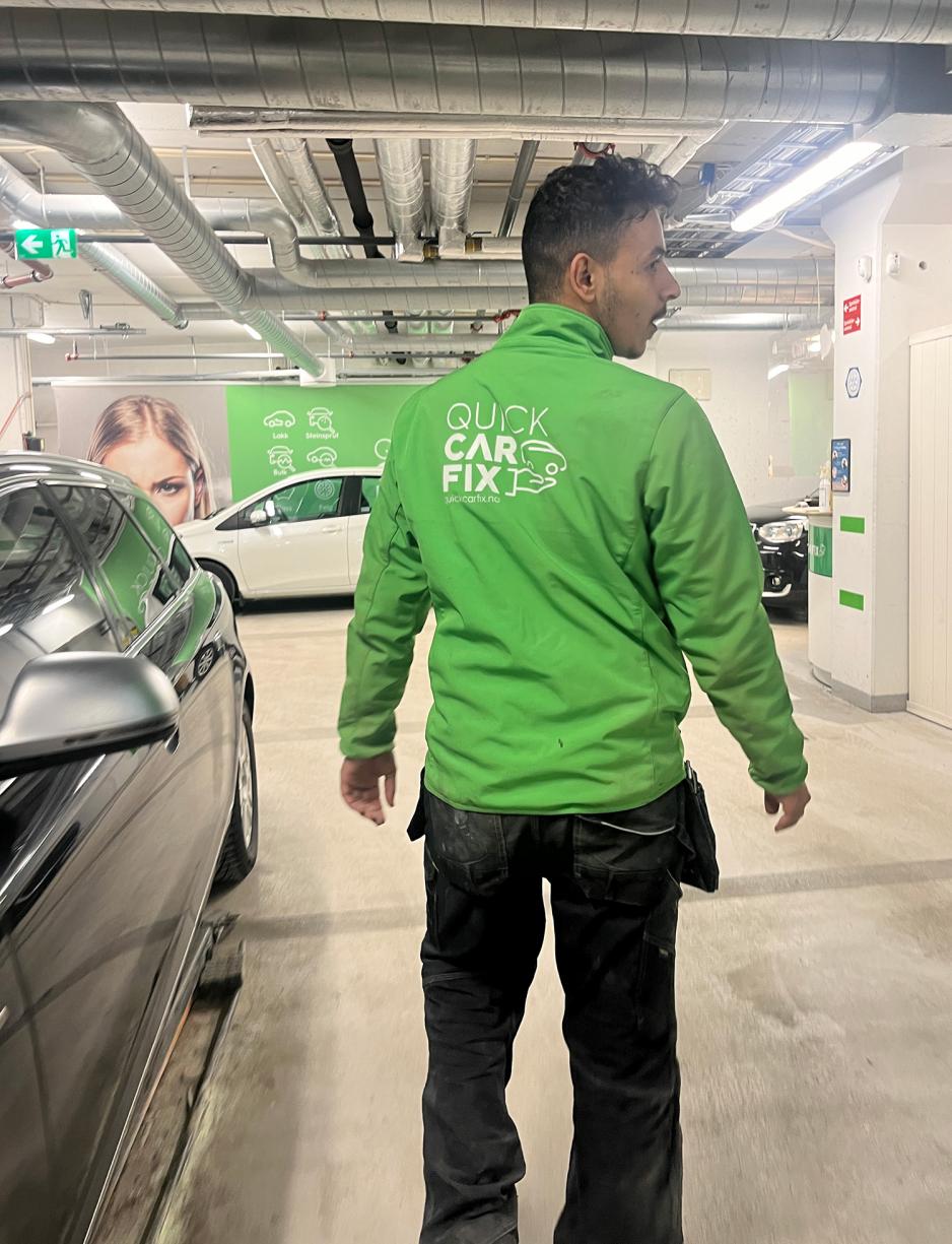 Bilde av ryggen til mann i gr&oslash;nn uniform i bilgarasje 