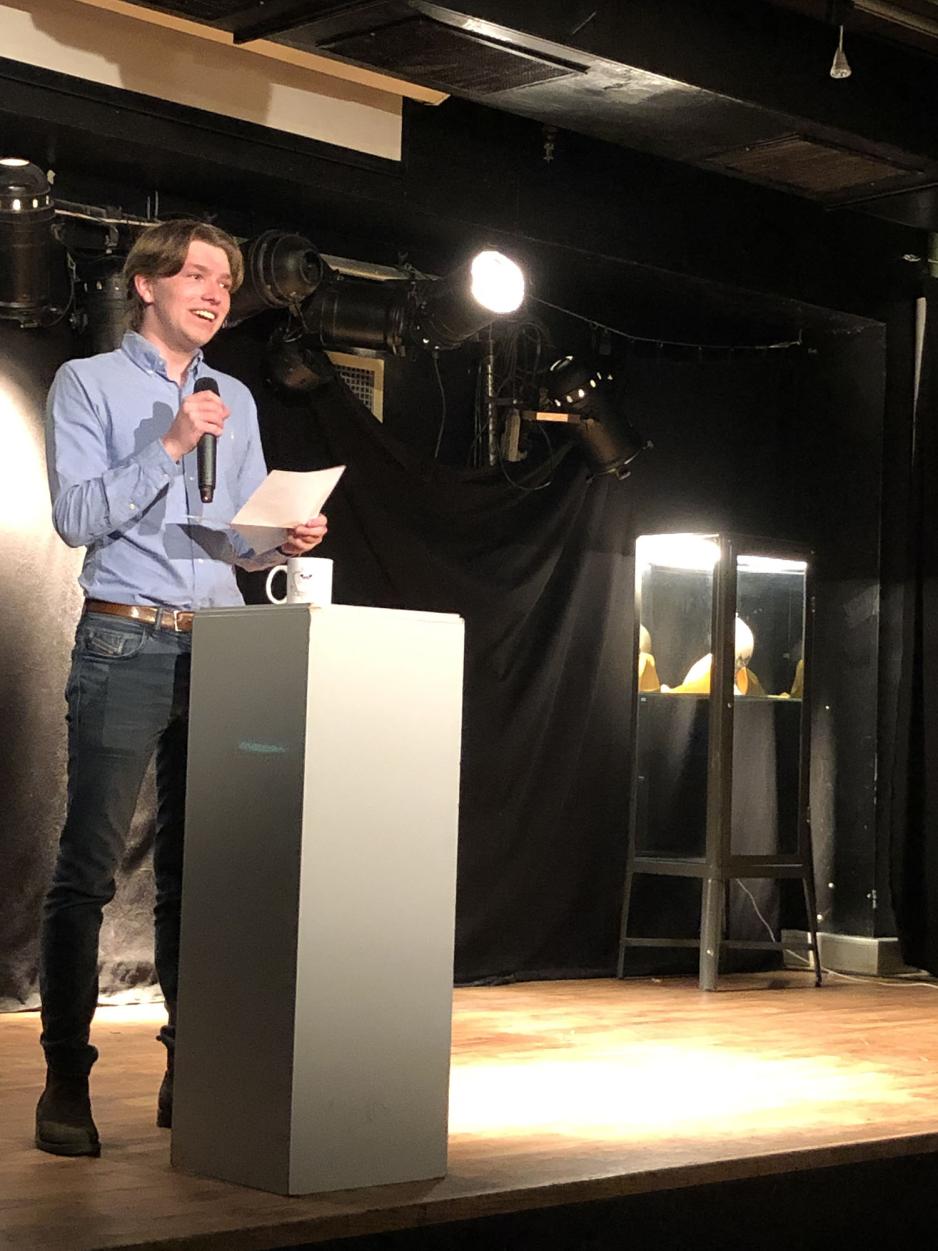 Henrik som st&aring;r p&aring; scenen, og holder tale foran studentene