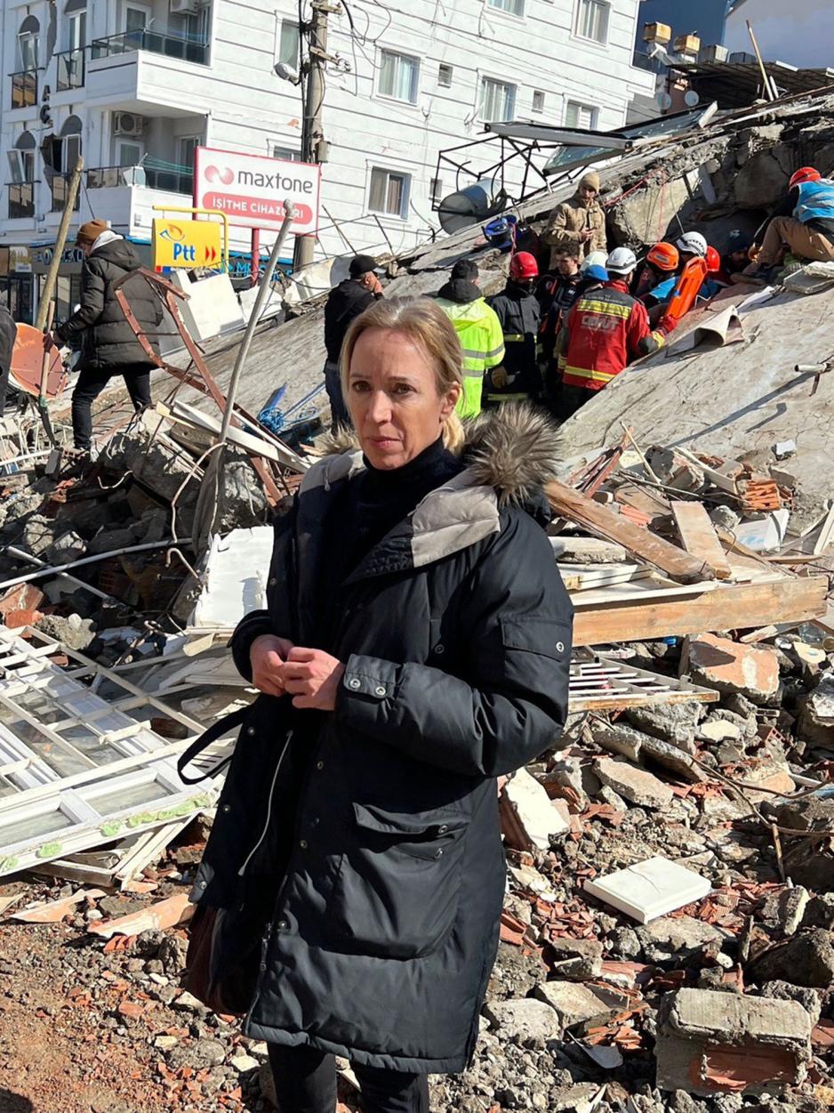 Portrett av journalist &Aring;se Marit. Bak henne foreg&aring;r hjelpearbeid i ruinene etter jordskjelvet. 