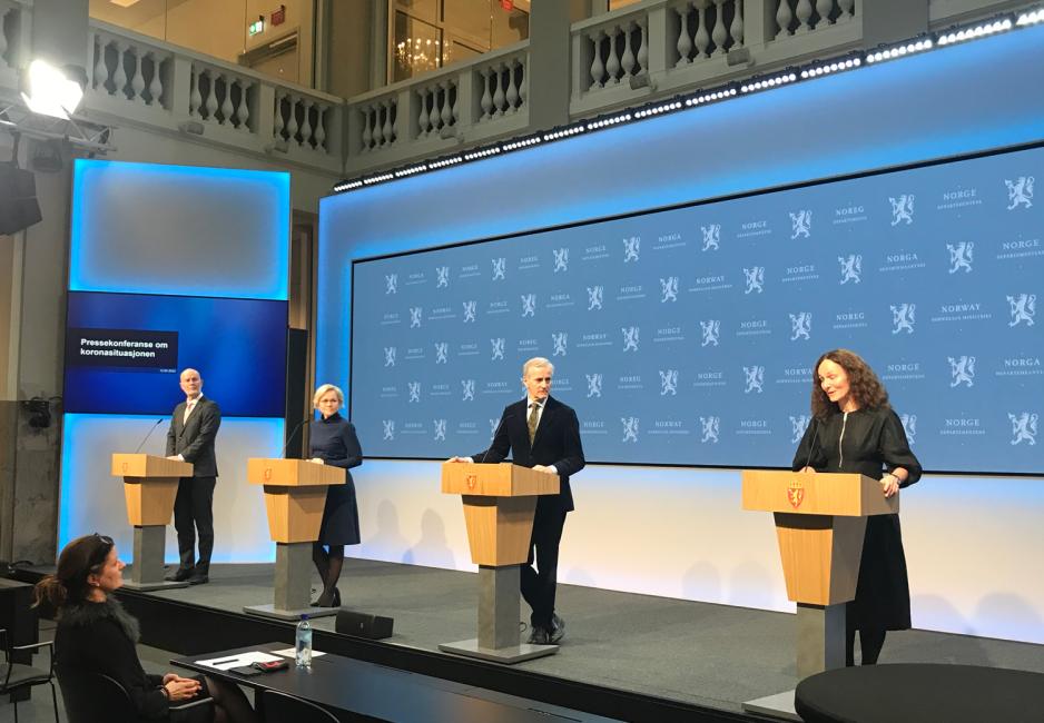 Bilde av at Camilla Stoltenberg snakker p&aring; pressekonferansen. De andre deltakerne f&oslash;lger med p&aring; det hun sier.