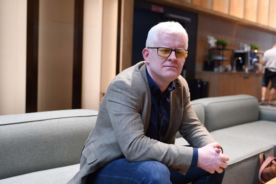 Et portrettbilde av Dag Idar Tryggestad, leder av Norsk journalistlag, sittende fremoverlent p&aring; en sofa, med foldede hender