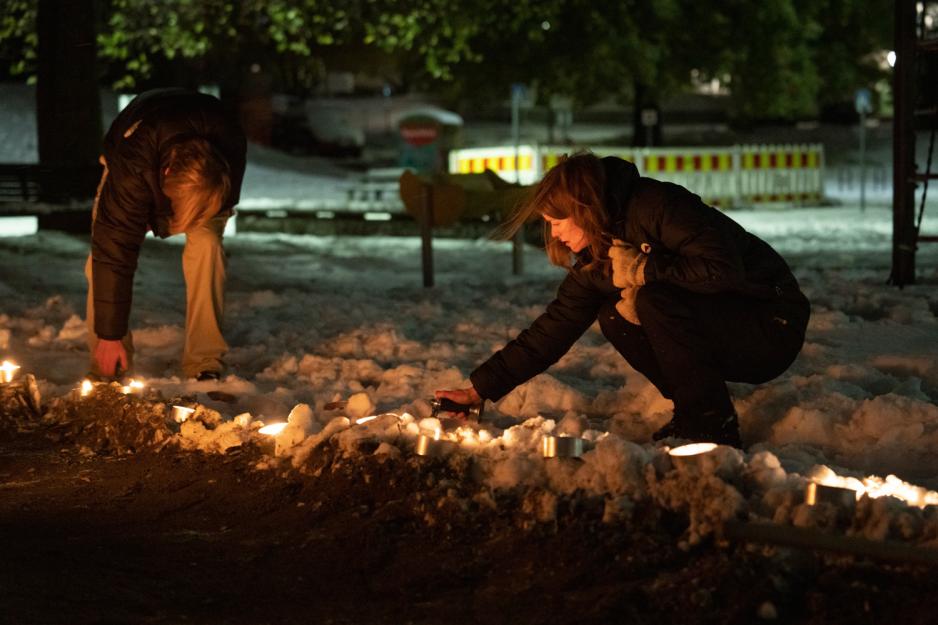 Kvinne sitter p&aring; huk og tenner p&aring; fakler i m&oslash;rket
