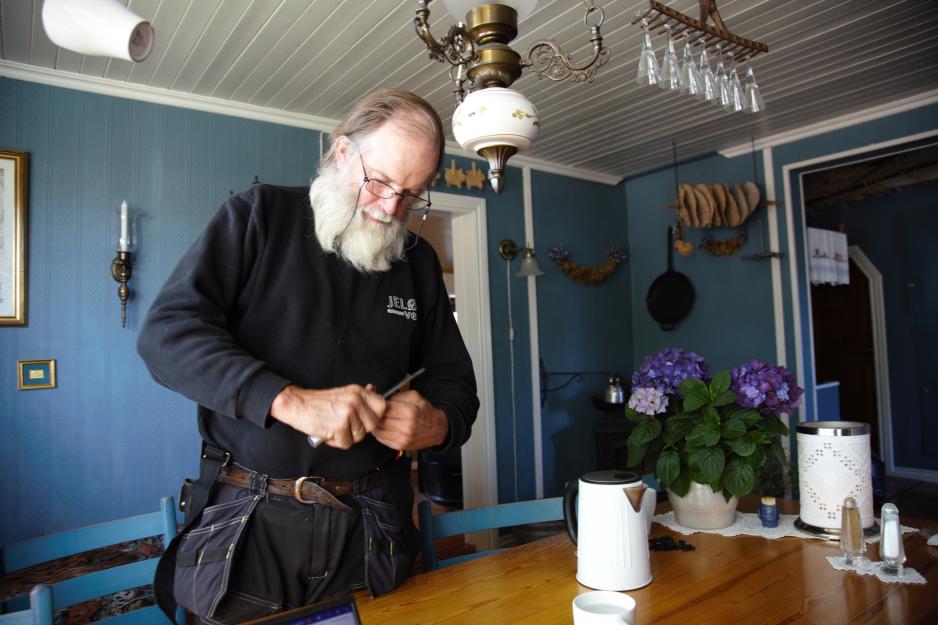 Einar Aas st&aring;r og kutter opp pulverkaffeposer med en kniv
