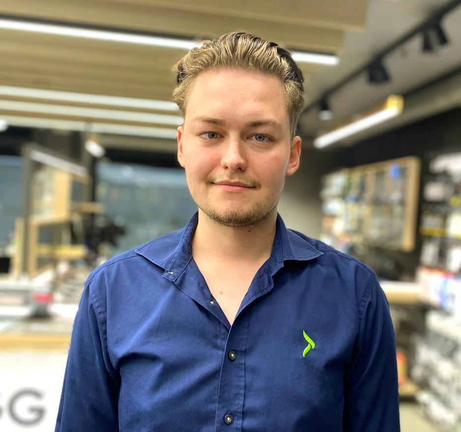 Portrett av Fabian Reinsborg. Han har kort blondt h&aring;r og en bl&aring; skjorte med Elkj&oslash;p sin logo p&aring;.
