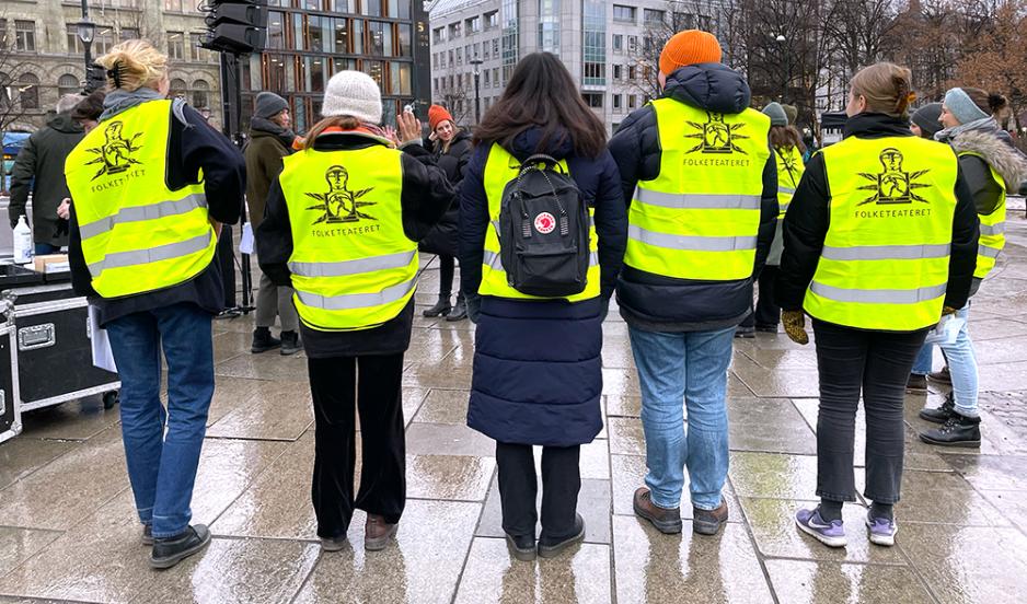 mennesker som  st&aring;r i gule vester