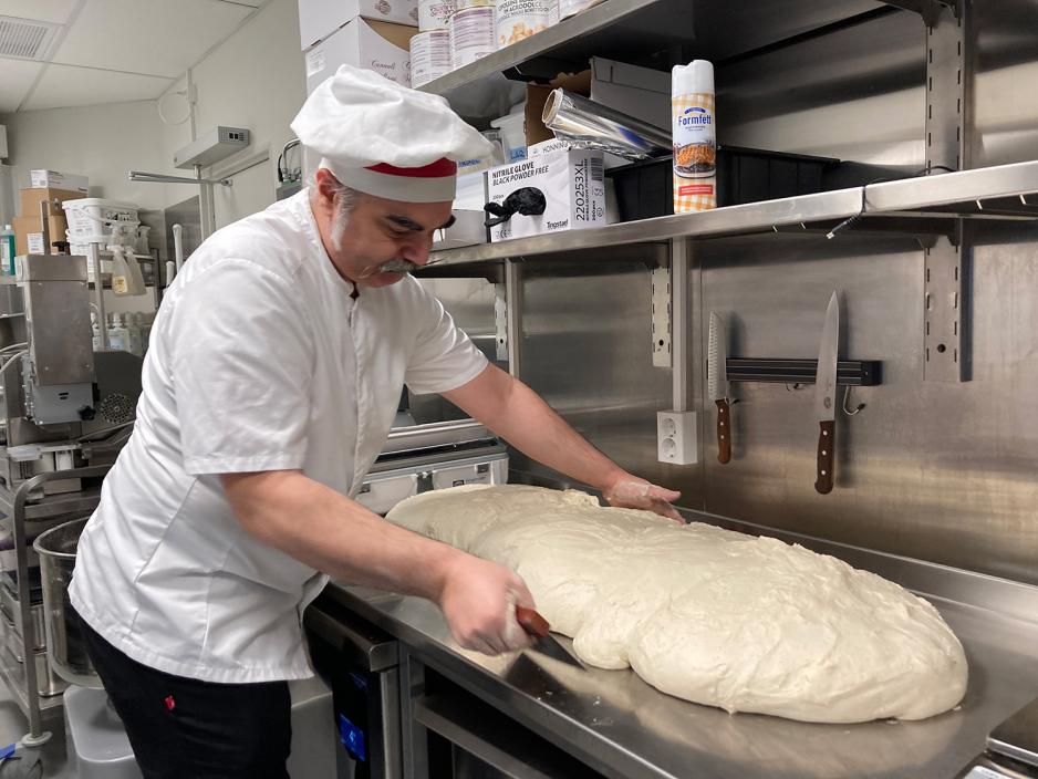 Inne p&aring; kj&oslash;kkenet i Trattoria Crudo lager Francesco De Palma en stor pizzadeig. 