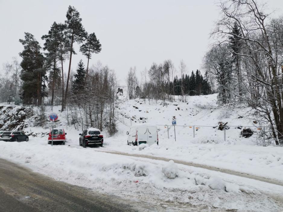 Bilde av parkerte biler foran en fjellvegg. Til h&oslash;yre og oppover er hogstfeltet til Slattumhallen