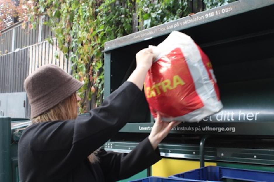Jente som legger en plastpose med kl&aelig;r i en UFF-container. 