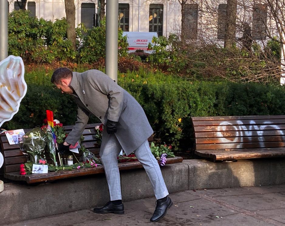Mann legger blomst p&aring; benk