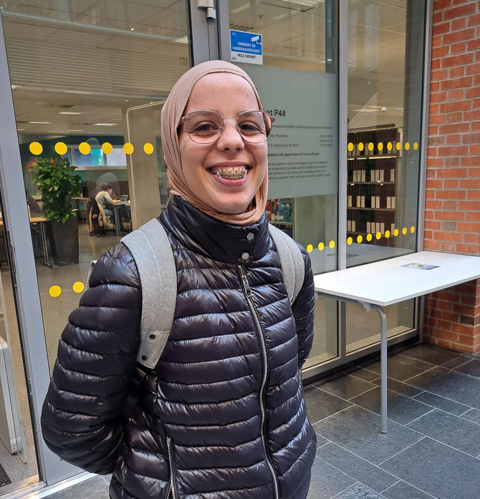 Amal Rahmati smiler med regulering utenfor biblioteket p&aring; OsloMet