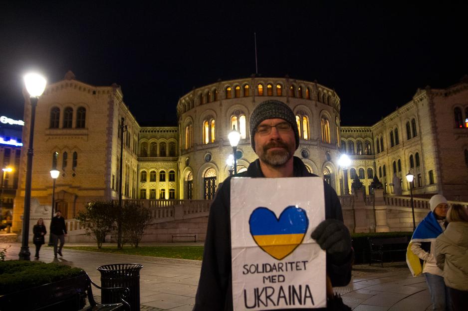 En mann st&aring;r med et skilt foran seg, foran Stortinget. 