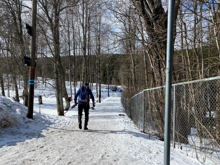 Mann med skiutstyr i hendene g&aring;r inn i l&oslash;ypa