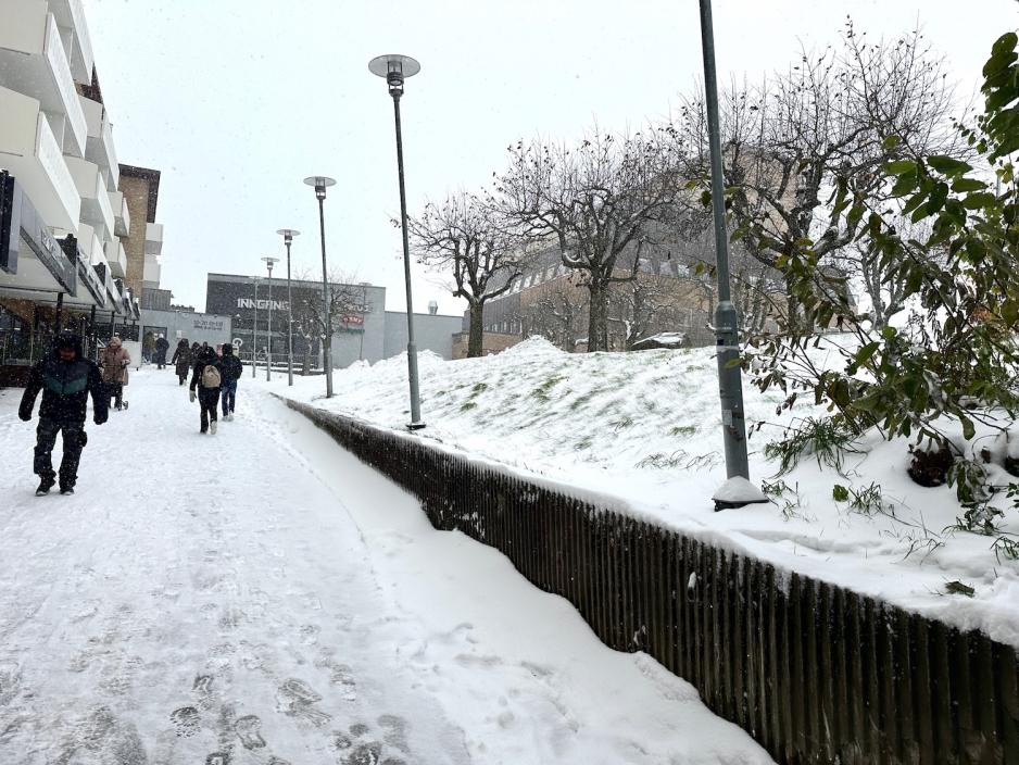Folk som g&aring;r ned bakken dekket av sn&oslash;. 
