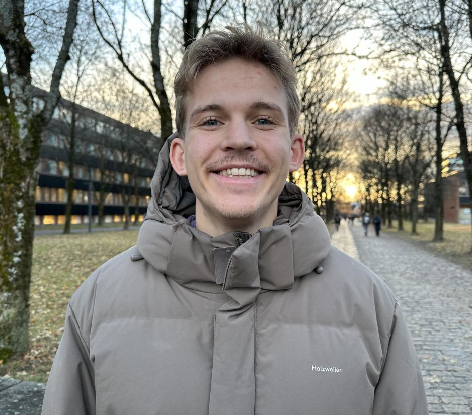 En gutt med m&oslash;rkt h&aring;r som smiler mot kamera