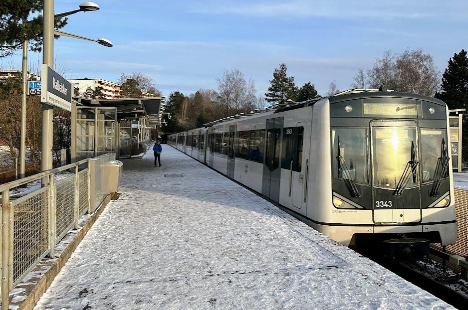 T-banen ankommer stasjonen p&aring; Kalbakken. Flere personer st&aring;r p&aring; perrongen. 