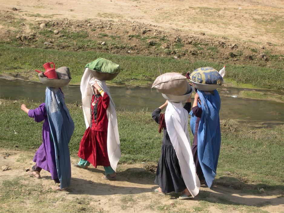 Kvinner b&aelig;rer sekker med klesvask ved Kabul-elven