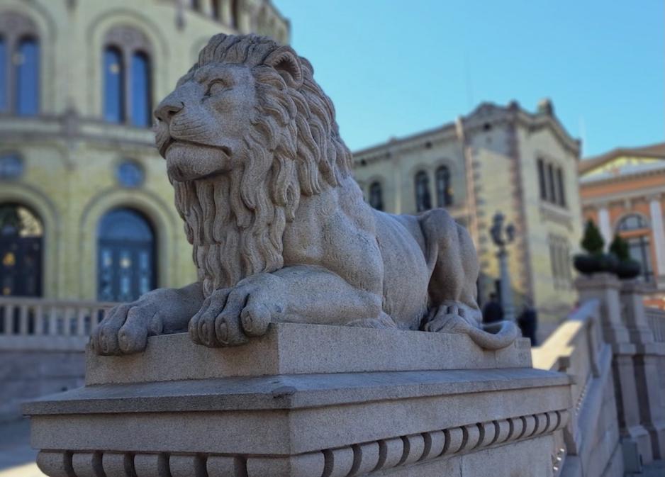 Granittskulptur av l&oslash;ve p&aring; L&oslash;vebakken med Stortinget i bakgrunnen.