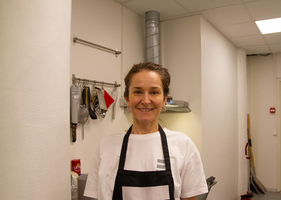 En brunh&aring;ret dame smiler mot kamera med et forkle. 