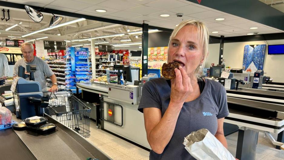 Monica Wickstr&oslash;m har nettopp betalt for handlen p&aring; Meny. Hun st&aring;r og spiser en kj&oslash;ttkake ved kassa.