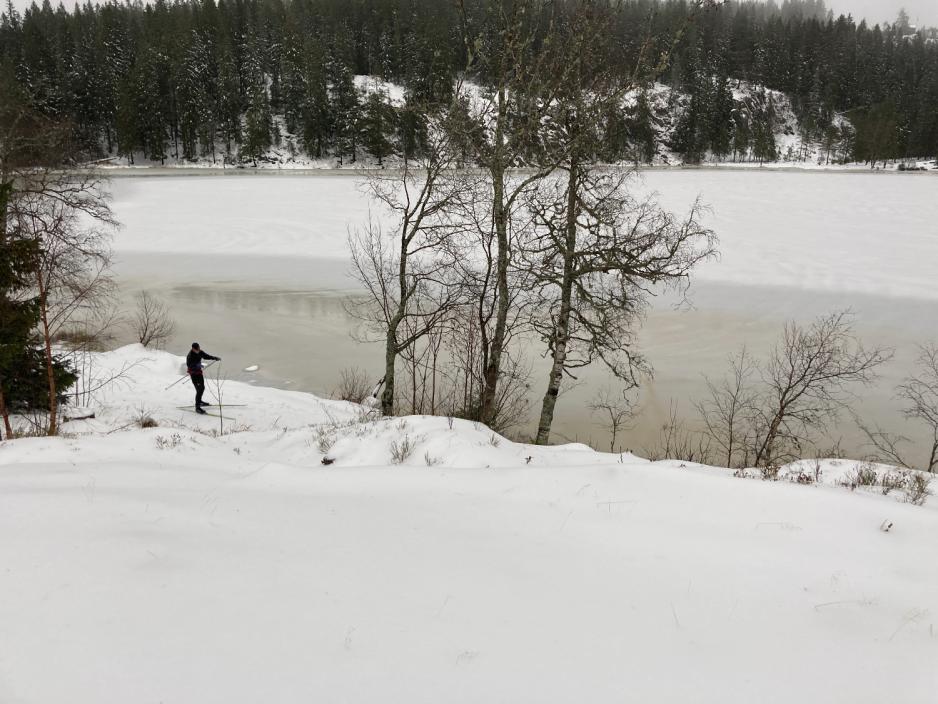 Bildet er av et vann ved Skjennungsvolden. Det er sn&oslash;, og en person fyker forbi p&aring; ski langs vannet. 