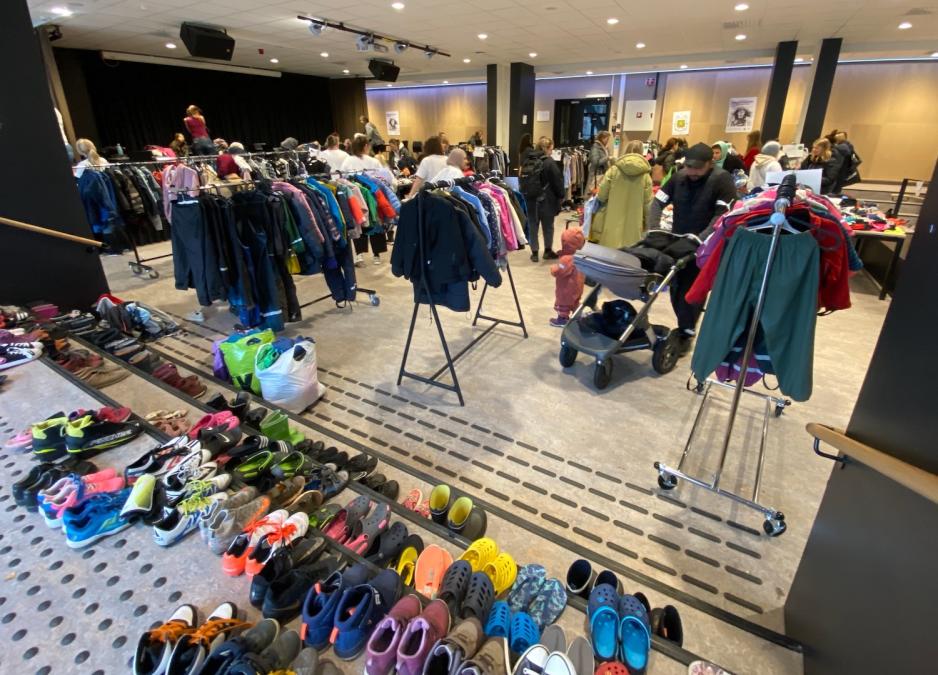 oversiktsbilde av klesbyttemarked med kl&aelig;r, sko og mennesker som titter