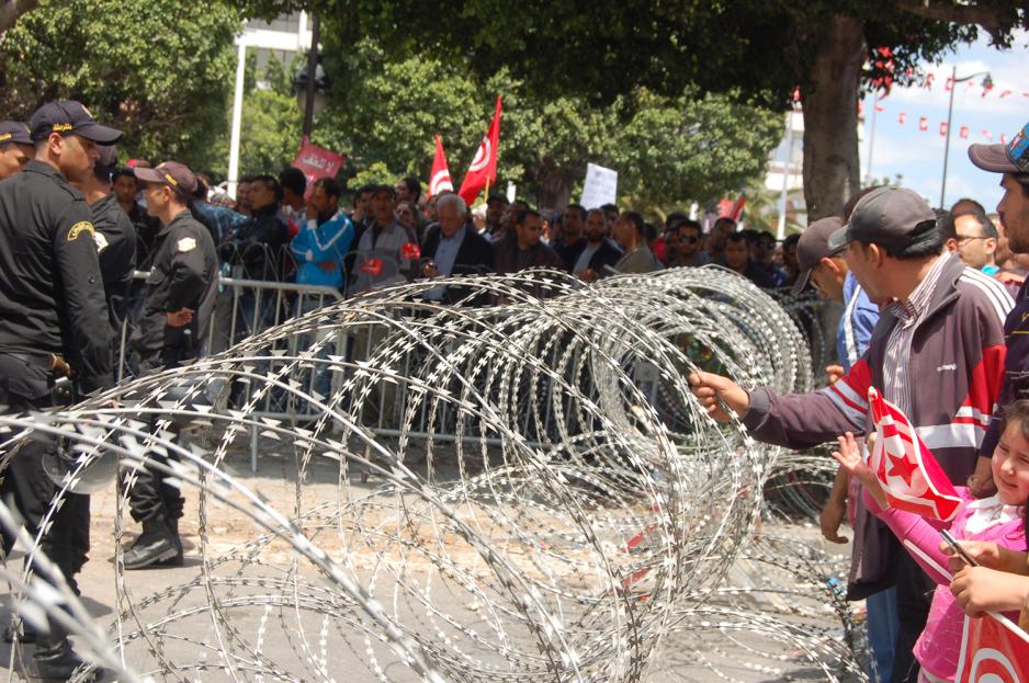 Noen folk som st&aring;r bak en piggtr&aring;d i Tunisia