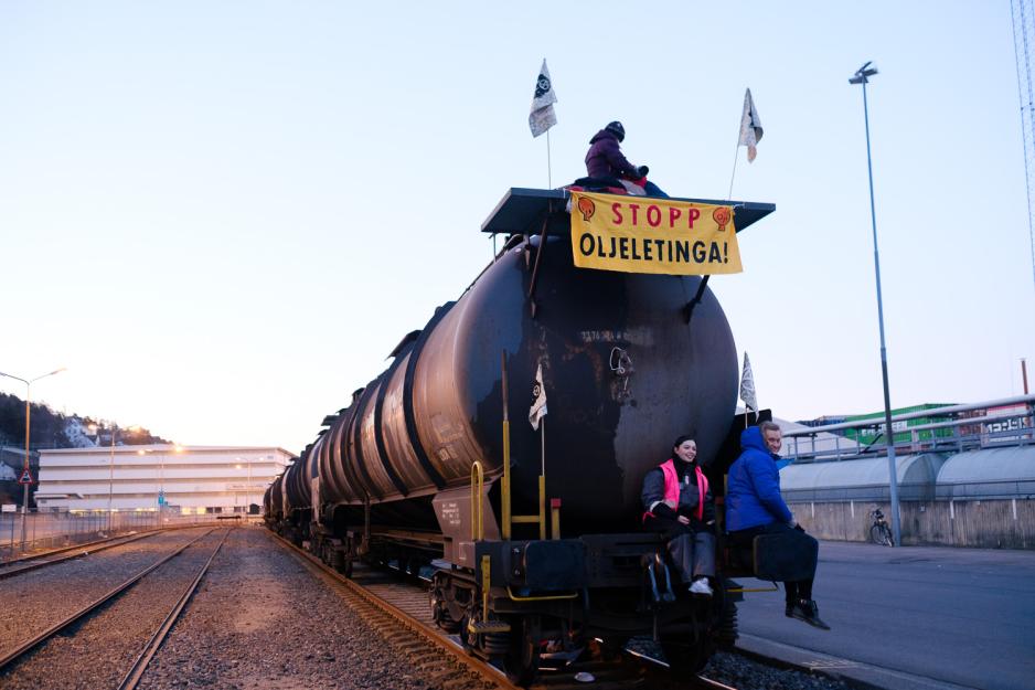 Aksjonister fra Extinction Rebellion sitter foran og opp&aring; tankvogner fylt med flybensin.