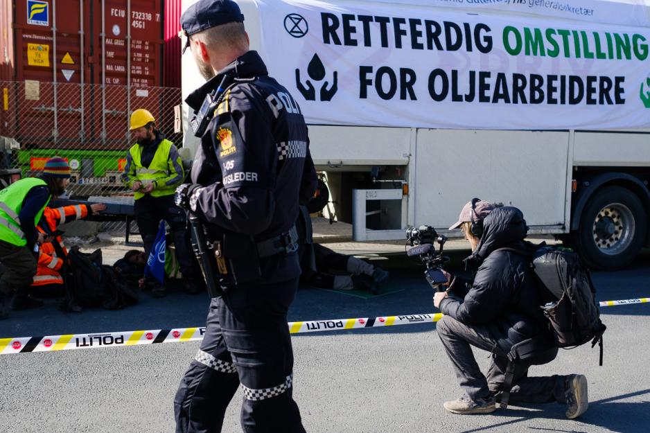 Thomas &Oslash;stbye filmer aksjonistene mens en politimann g&aring;r forbi.