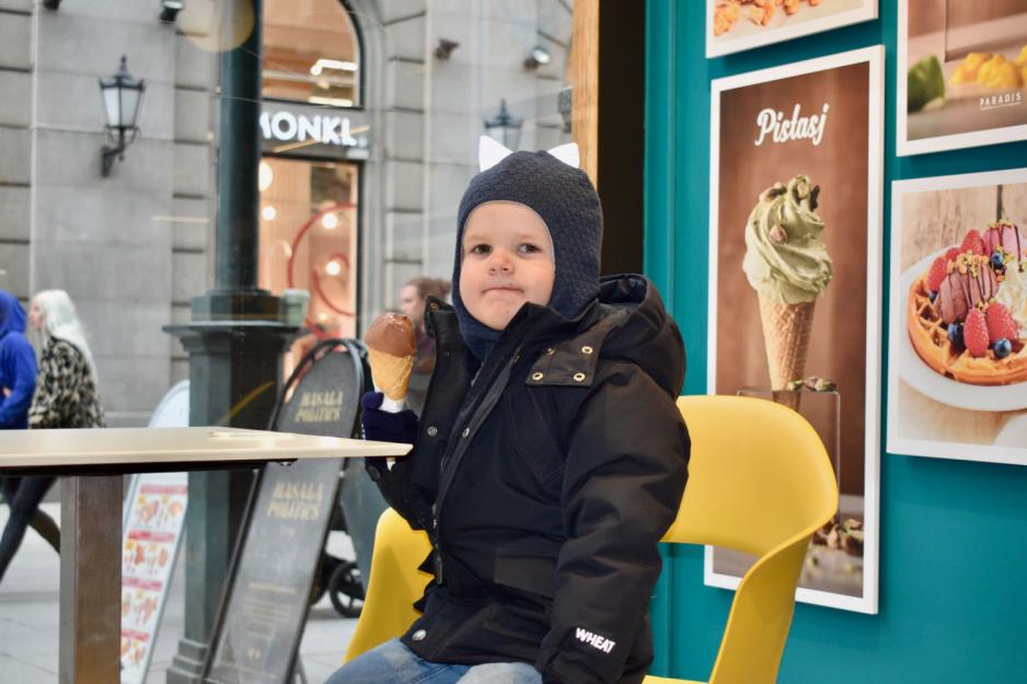 Liten gutt spiser sjokoladeis i kjeks. Han har p&aring; seg m&oslash;rkebl&aring; vinterjakke og m&oslash;rkebl&aring; lue. 