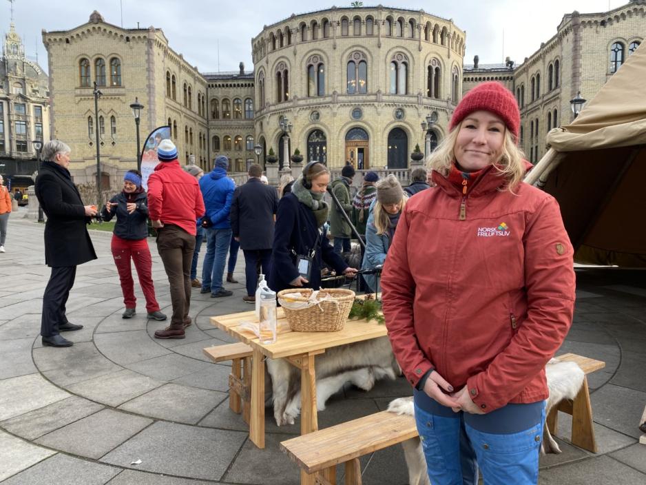Synne Kvam i Norsk Friluftsliv i r&oslash;d jakken utenfor Stortinget ved en lavo. 