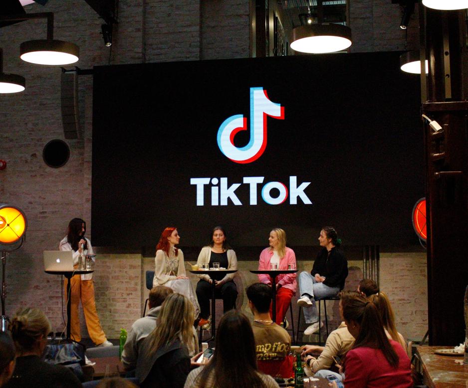 Debatt med fem mennesker p&aring; scenen foran en skjerm med stor tiltok logg p&aring; seg. 