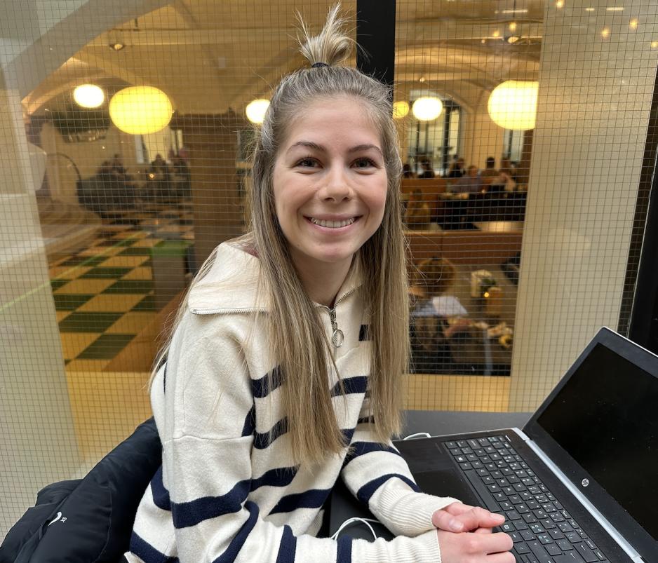 En jente med blondt h&aring;r som smiler mot kamera