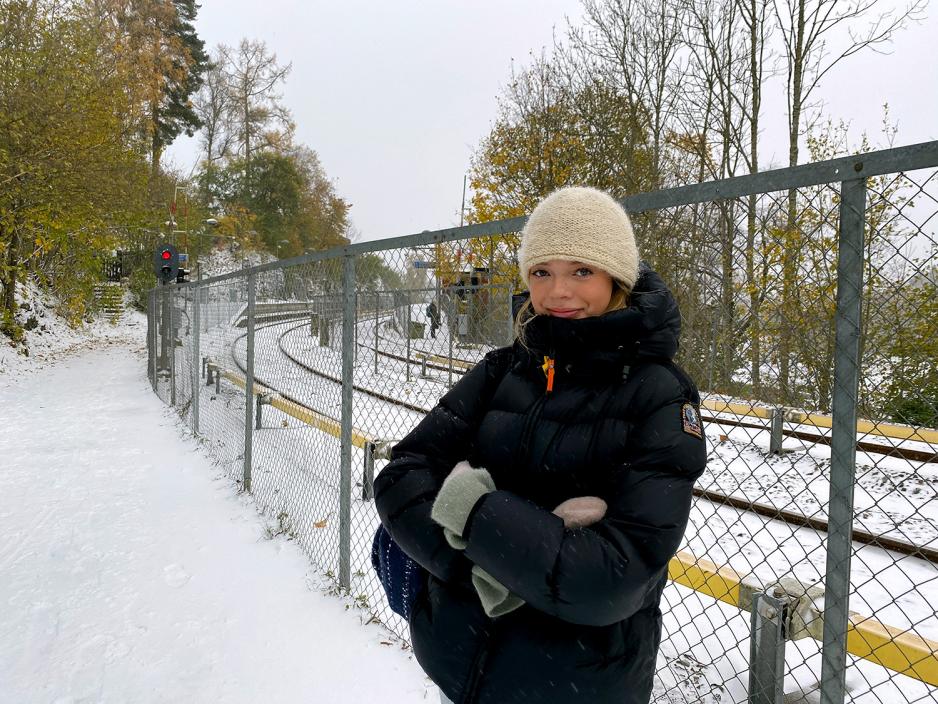 Jente st&aring;r og venter p&aring; T-banen p&aring; Gr&aring;kammen stasjon. Det sn&oslash;r.