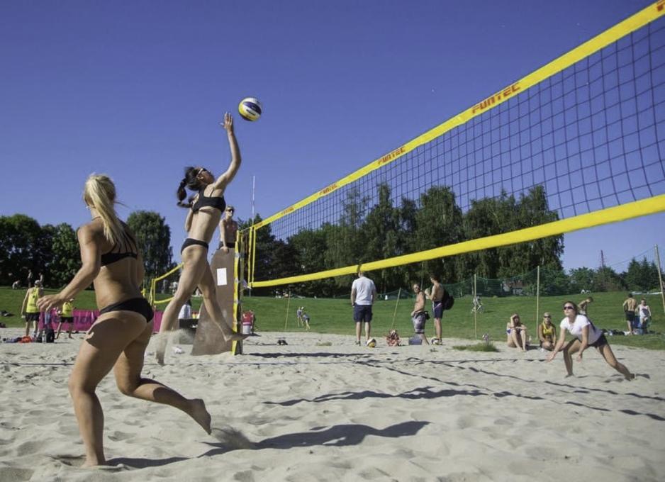 Kritkamchon spiller sandvolleyball. Hun hopper og er p&aring; vei til &aring; sl&aring; ballen over det gule nettet.