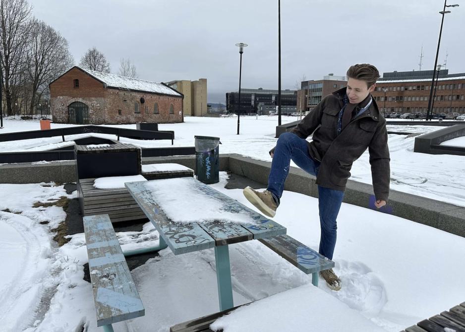 En ung gutt som sparker vekk sn&oslash;en fra en benk