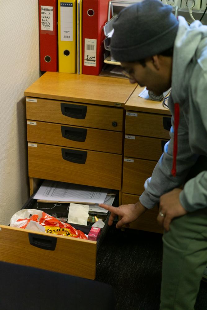 Adeel viser frem skuffen p&aring; kontoret sitt fylt med f&oslash;rstehjelpsartikler, kj&aelig;rlighet p&aring; pinne, covid-tester, gnags&aring;rplaster og tamponger. 