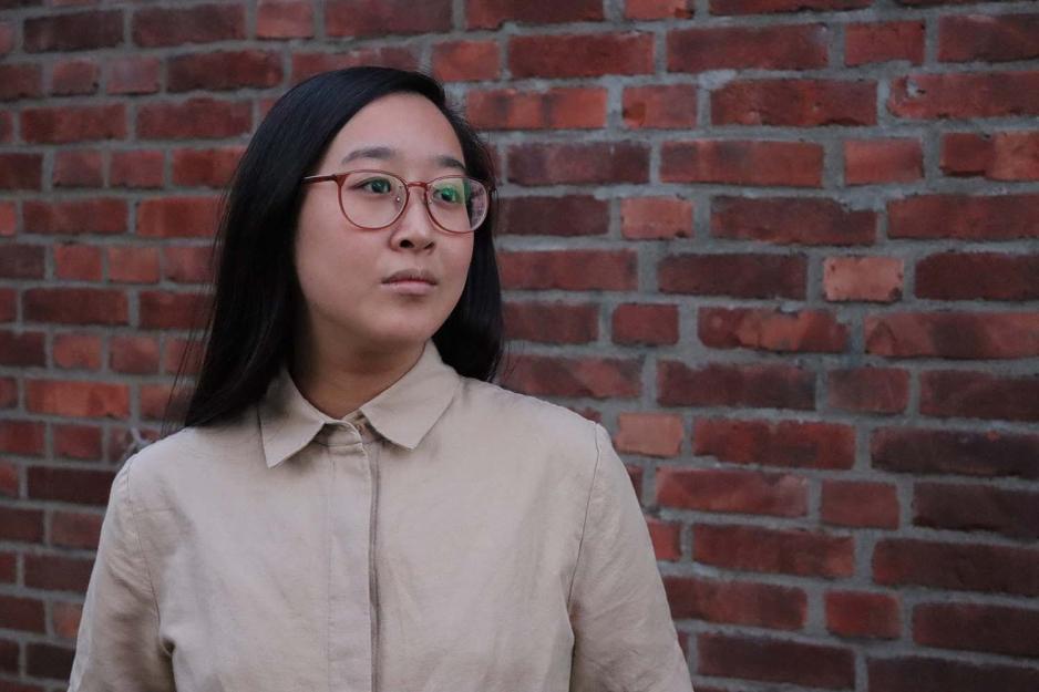 VG-journalist Xueqi Pang st&aring;r foran en murvegg og ser bort fra kamera