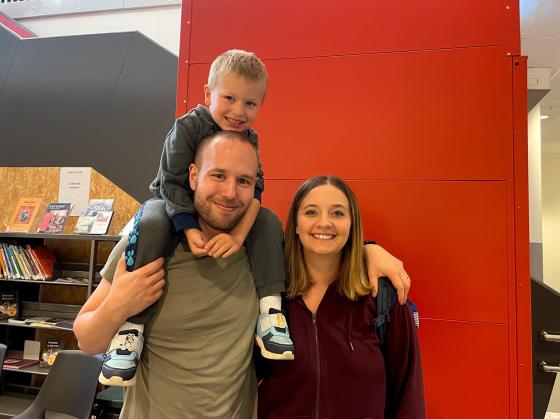 S&oslash;nnen sitter p&aring; faren sin rygg mens han holder rundt kona. Alle smiler.