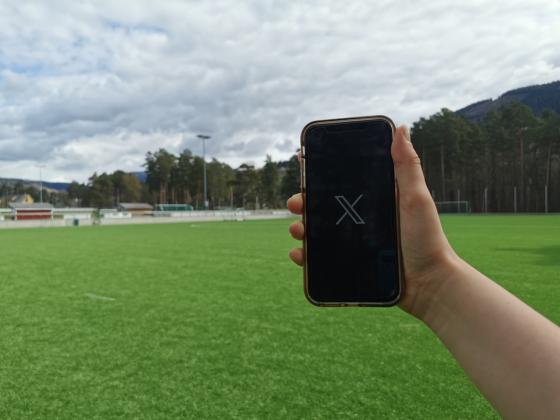 Telefon med X-logo ved fotballbane