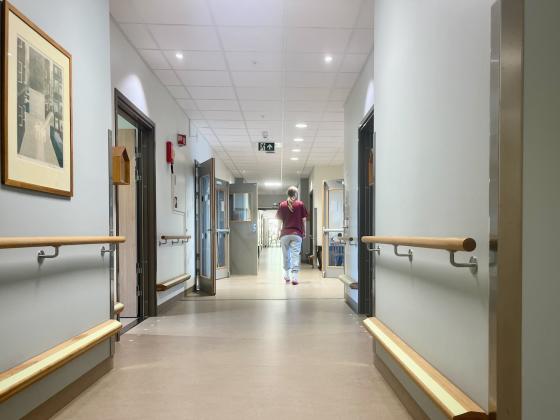 Sykepleier g&aring;r nedover gangen p&aring; et sykehjem