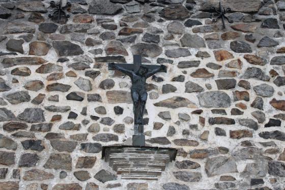 P&aring; en steinvegg, henger et kors med Jesus p&aring;
