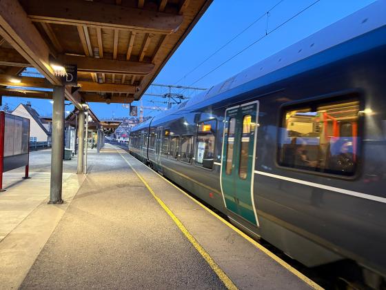 Toget kj&oslash;rer i full fart p&aring; Sk&oslash;yen stasjon