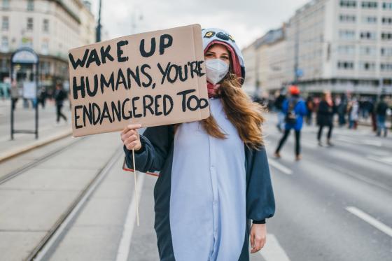 Demonstrant med et skilt hvor det st&aring;r at mennesker ogs&aring; er utrydningstruet. 
