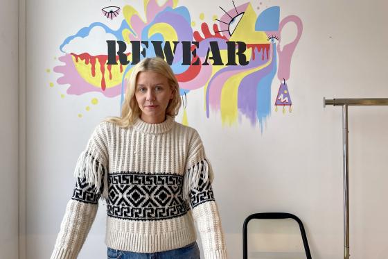 Daglig leder Arna Margr&eacute;t &AElig;gisd&oacute;ttir st&aring;r foran den fargerike logoen til butikken Rewear.